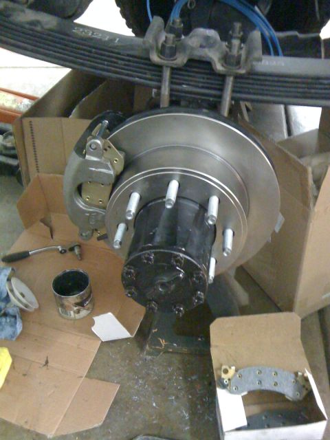 1988 Ford Bronco - Close-up of a vehicle's axle and brake assembly, with tools and packaging scattered around.