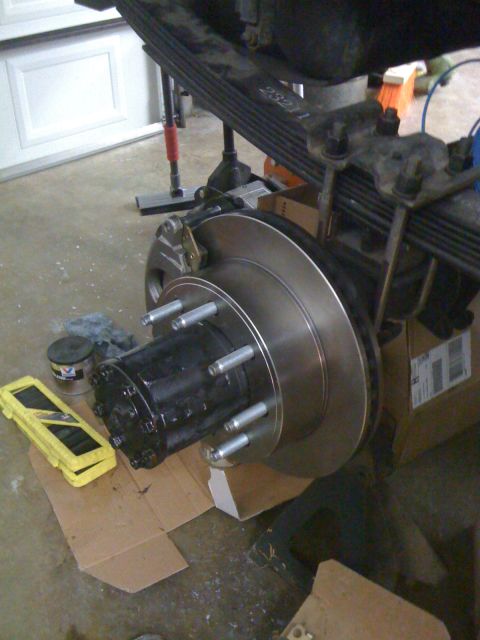 1988 Ford Bronco - Close-up view of a rear axle assembly, a disc brake rotor and hub with multiple lug studs.