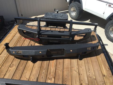 1988 Ford Bronco - Two aftermarket bumpers are displayed on a trailer, with a white Ford Bronco partially visible in the background.