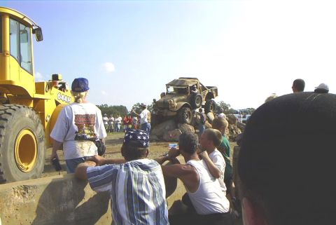 1995 Ford Bronco - A crowd watches as a vintage military truck navigates an obstacle course of large rocks.