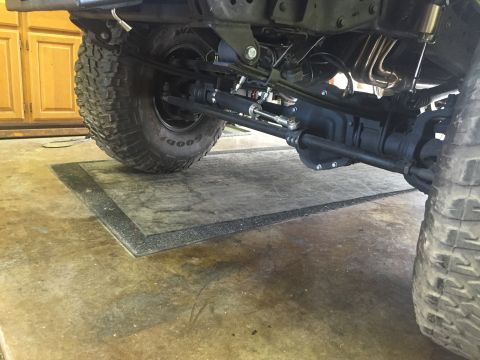 1988 Ford Bronco - Undercarriage view of a vehicle's front axle and suspension system, showing steering components and exhaust.
