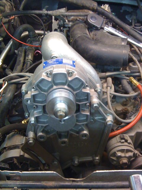1988 Ford Bronco - Close-up of a supercharger unit installed in an engine bay, with visible hoses and wiring.