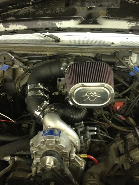 1988 Ford Bronco - Close-up view of a vehicle's engine bay a supercharger and aftermarket air intake system.