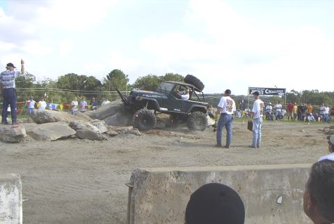 1995 Ford Bronco - An off-road vehicle tackles a challenging course during a competition, with onlookers gathered to watch the event.