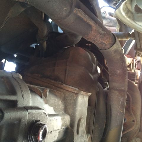 1988 Ford Bronco - Close-up view of the exhaust system and transmission components on the underside of a vehicle.