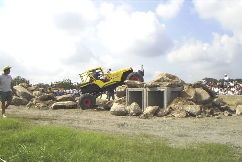 1995 Ford Bronco - Off-road vehicle tackles a challenging rock obstacle course with spectators observing.