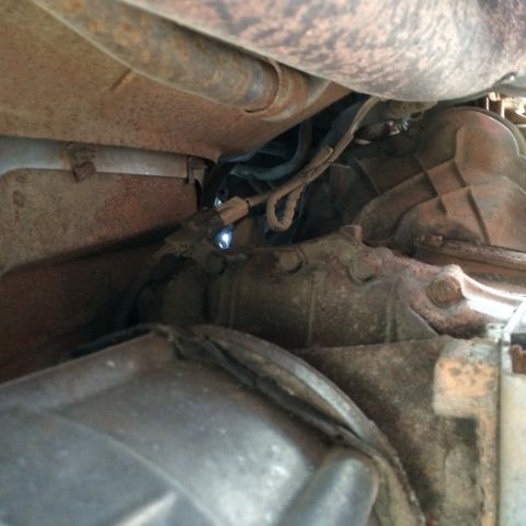 1988 Ford Bronco - Close-up view of the undercarriage, focusing on the exhaust and transmission components of a vehicle.