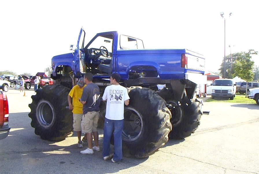 Blue Chevrolet monster truck on huge flotation tires with spectators in a show lot