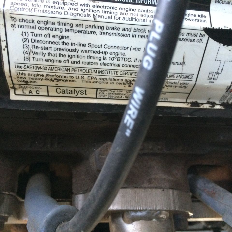 Spark plug wire labeled "PLUG WIRE" over a label with engine timing instructions and "Catalyst" text
