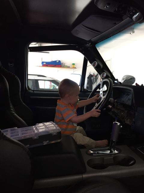 1988 Ford Bronco - Youngster pretends to drive, with a toolbox nearby in the vehicle's interior.