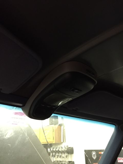 1988 Ford Bronco - Close-up of a dark gray overhead console mounted near the windshield on a vehicle headliner, shot from below.