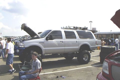 1995 Ford Bronco - Modified silver SUV on display at an outdoor event, hood is open showing the engine bay.