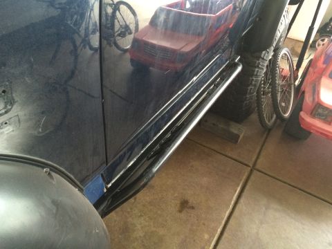 1988 Ford Bronco - A dark blue SUV is parked next to other vehicles and bicycles, with a focus on its side and rock sliders.