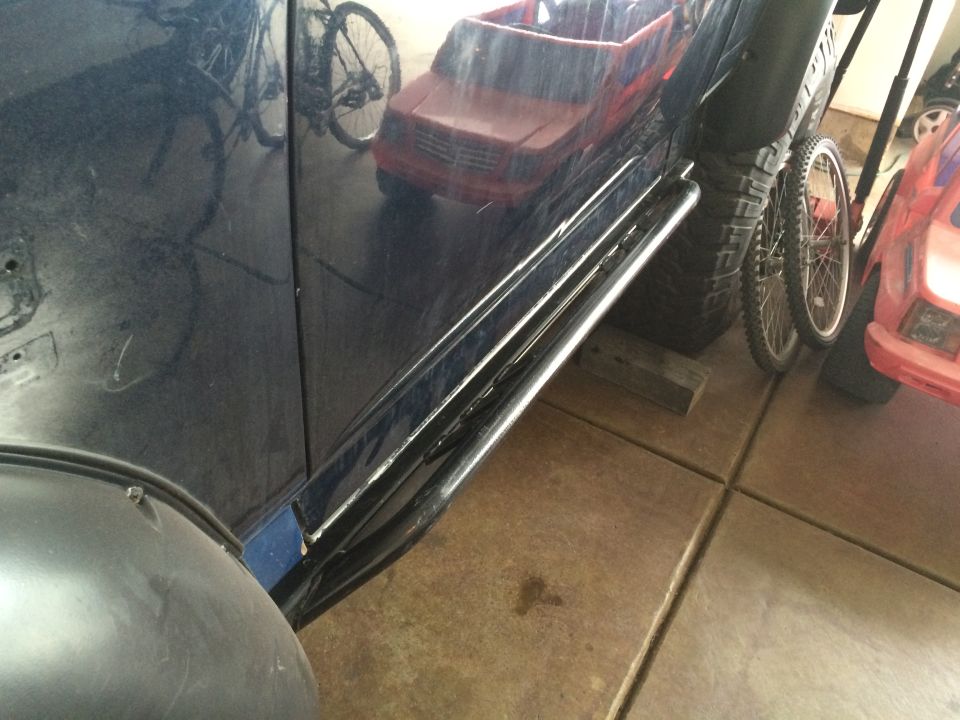 Dark blue SUV side view showing chrome rock sliders and a large tire