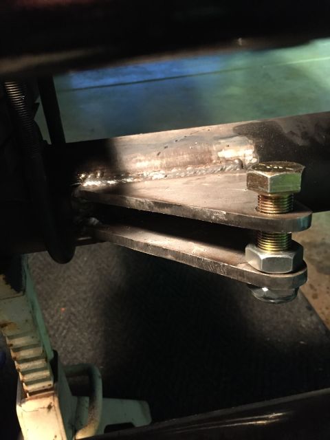 1988 Ford Bronco - A close-up view shows a metal bracket welded to a round tube, secured by a bolt and nut assembly. The bracket appears to be part of a suspe…