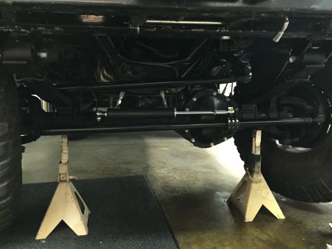 1988 Ford Bronco - The underside of a vehicle is shown supported by two jack stands. A heavy-duty steering stabilizer is installed on the front axle, connecti…