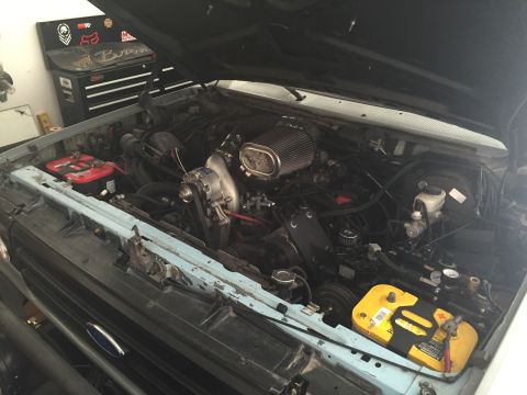 1988 Ford Bronco - The engine bay of a light blue Ford Bronco is shown with the hood open. Visible components include a supercharger, air filter, two batterie…