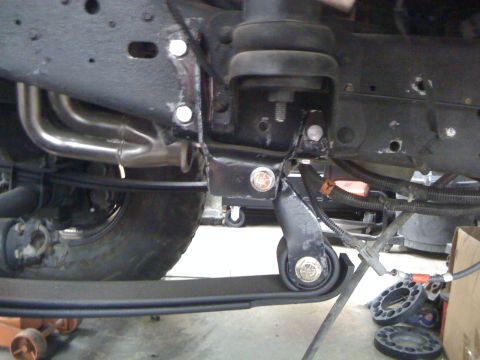 1988 Ford Bronco - Close-up view of the undercarriage of a vehicle, showing the exhaust manifold, leaf springs, and suspension components. The scene appears t…