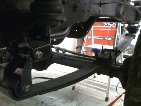 1988 Ford Bronco - This is a close-up, low-angle shot of the suspension system of a vehicle, likely a truck or SUV. It shows leaf springs, U-bolts, and mounti…