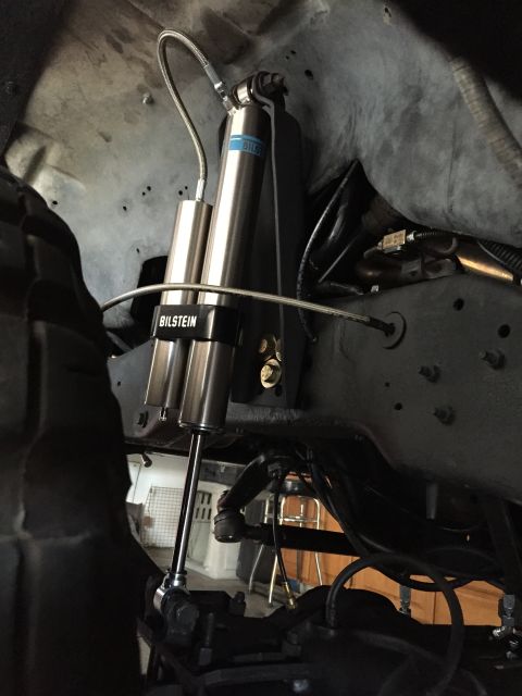 1988 Ford Bronco - A close-up view of the suspension system of a vehicle, featuring dual Bilstein shock absorbers mounted to the frame. The shocks are silver…