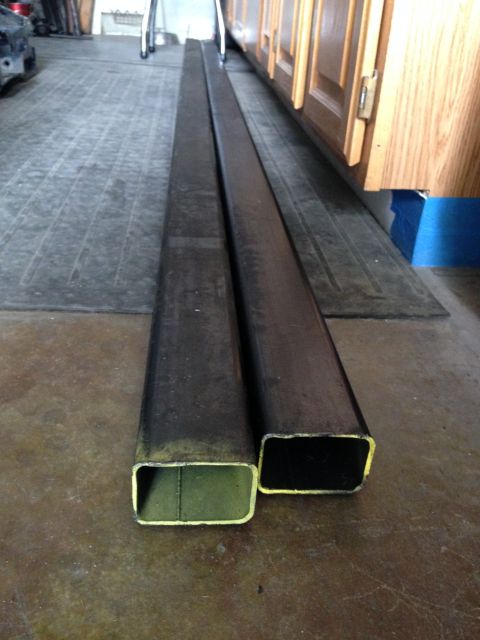 1988 Ford Bronco - Two long, rectangular metal tubes are lying on a concrete floor in what appears to be a garage or workshop. One tube is slightly wider than…