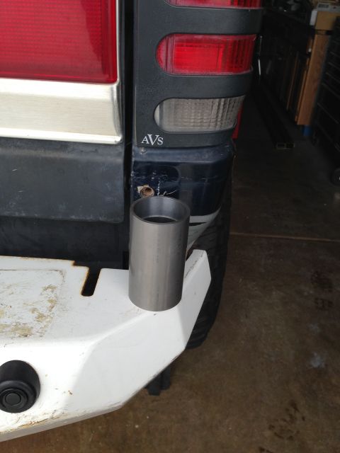1988 Ford Bronco - A close-up view of the rear corner of a dark blue SUV, showing a portion of the taillight assembly and a silver metal tube resting on a whi…
