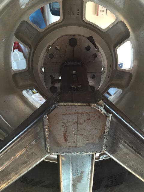 1988 Ford Bronco - A close-up view of a custom metal fabrication attached to the hub of a vehicle wheel. The fabrication appears to be part of a jig or stand,…
