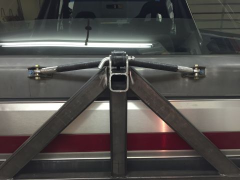 1988 Ford Bronco - A custom-fabricated metal swing-away spare tire carrier is mounted to the rear of a vehicle. The carrier features a central square tube rec…