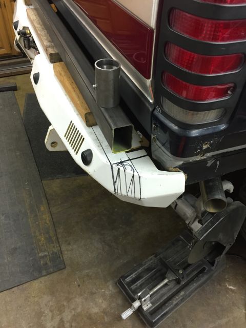 1988 Ford Bronco - A custom metal bumper is being fabricated and fitted to the rear of a dark-colored SUV. Metal tubing and a chop saw are visible in the work…