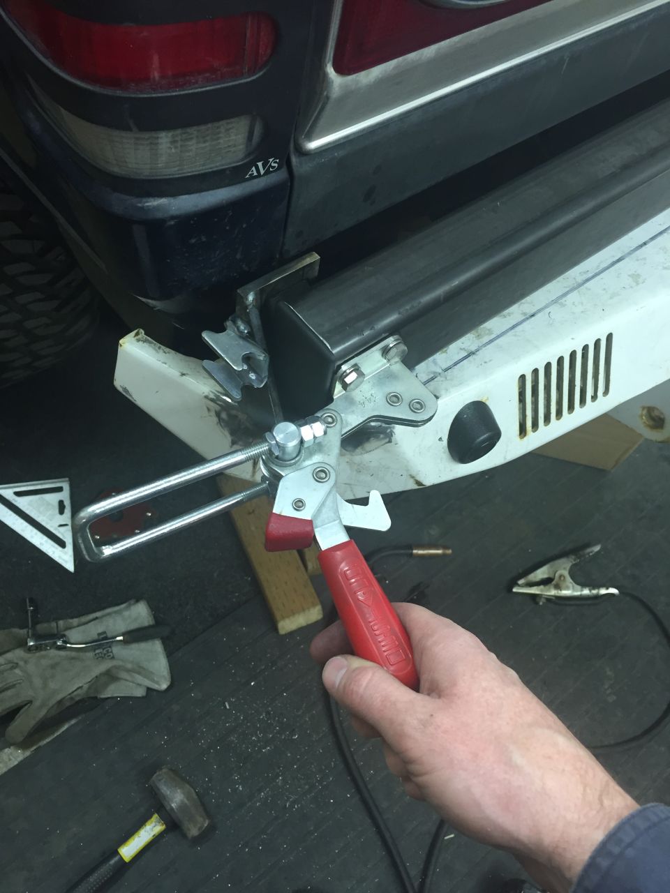 Welding clamp attached to custom metal bumper on rear of dark blue SUV.