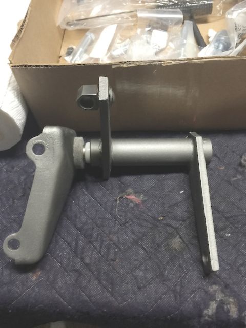 1978 Ford Bronco - A metal mechanical linkage assembly is shown resting on a quilted dark fabric surface. The assembly includes a cylindrical shaft with two a…