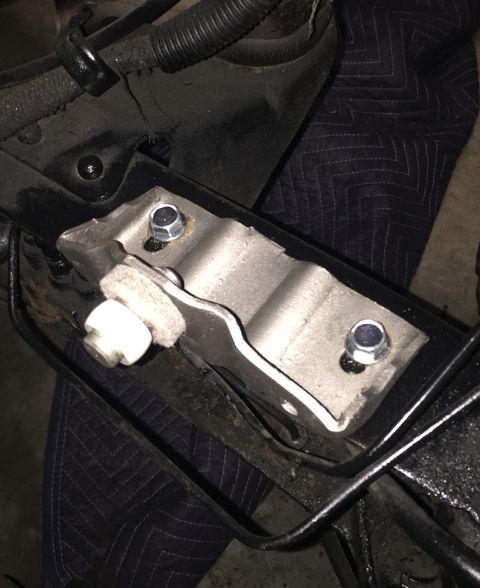 1978 Ford Bronco - A close-up view shows a metal bracket bolted to a black frame component, likely part of a vehicle's suspension or chassis. A quilted dark b…