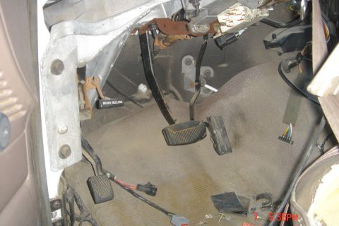 1988 Ford Bronco - The interior driver's side footwell of a vehicle shows the brake and clutch pedals, along with wiring and a "BRAKE RELEASE" label.