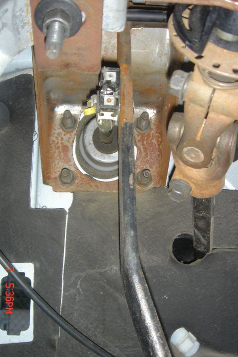 1988 Ford Bronco - This is a close-up view of the brake pedal assembly inside a vehicle, showing the brake light switch and part of the steering column mechan…