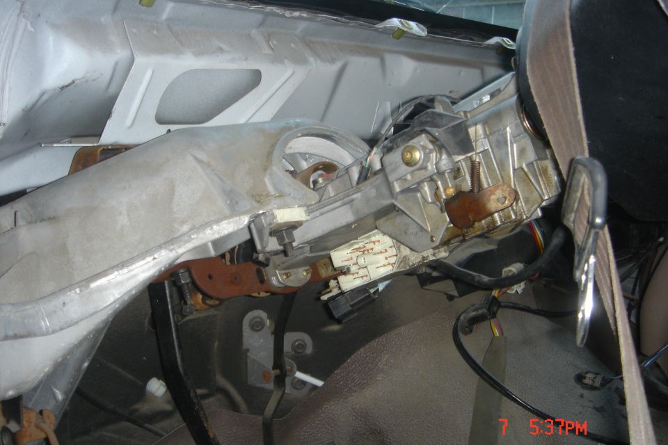 Disassembled vehicle dashboard showing steering column, ignition, and wiring.