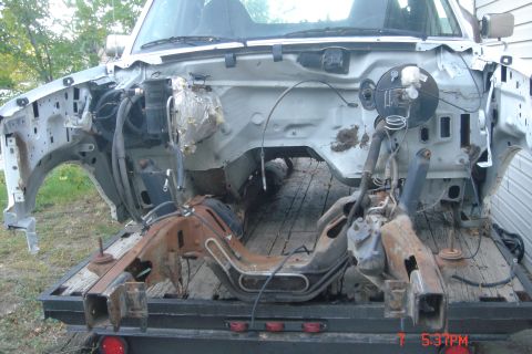 1988 Ford Bronco - The front end of a disassembled vehicle, likely a truck or SUV, is shown mounted on a flatbed trailer. The frame, suspension components, an…