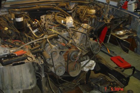 1988 Ford Bronco - The engine bay of a Ford Bronco is shown with the engine partially disassembled. Various hoses, belts, and engine components are visible, a…