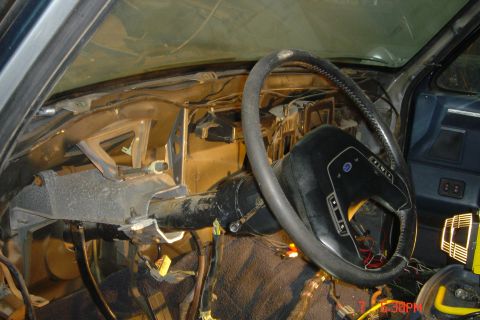 1988 Ford Bronco - The interior of a disassembled vehicle, showing the steering column, dashboard structure, and wiring. The steering wheel is visible with so…