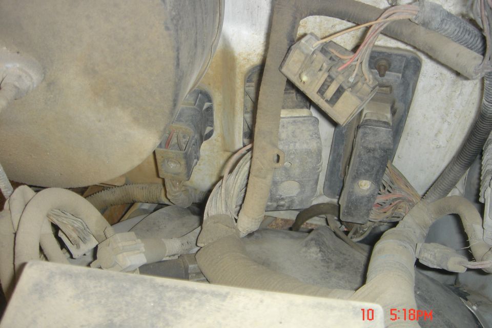 Dusty electrical connectors and wiring harnesses in a vehicle engine bay.