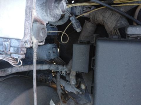 1988 Ford Bronco - This image shows a close-up view of a vehicle's engine bay, focusing on a black fuse box and a smaller gray relay box with visible wiring a…