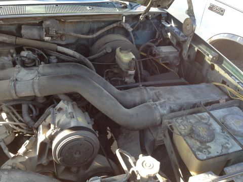1988 Ford Bronco - A close-up view of the engine bay of a green Ford truck, showing the air intake system, air conditioning compressor, and brake fluid reserv…