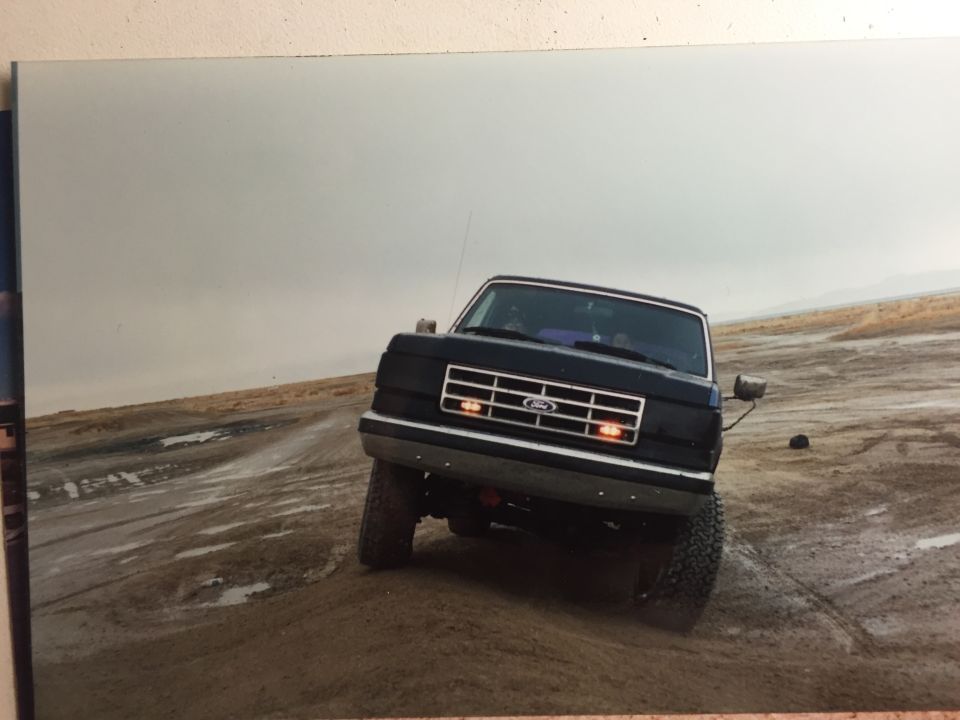 1988 Ford Bronco driving on wet, muddy terrain