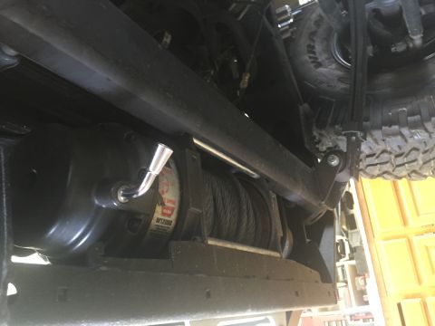 1988 Ford Bronco - The underside of a vehicle shows a large winch mounted to the frame, with a tire visible above and to the right. The winch has a silver han…