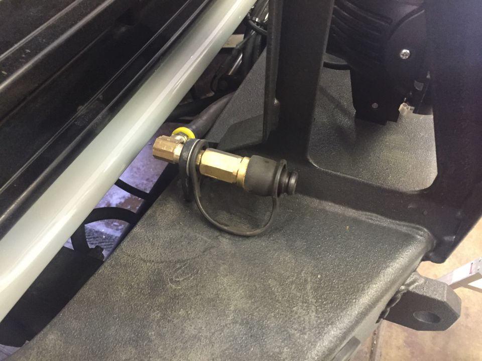 Brass air chuck with dust cap on black vehicle bumper