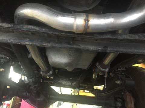 1988 Ford Bronco - The underside of a vehicle shows a custom exhaust system with a large diameter pipe welded together and routed over the frame. Various susp…