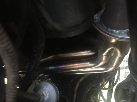 1988 Ford Bronco - A close-up view shows the exhaust manifold and piping of a vehicle, with visible heat discoloration on the metal pipes. The engine bay also…