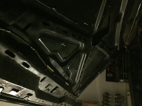 1988 Ford Bronco - The underside of a vehicle's hood is shown, revealing structural reinforcements and some wiring. The hood appears to be painted black.
