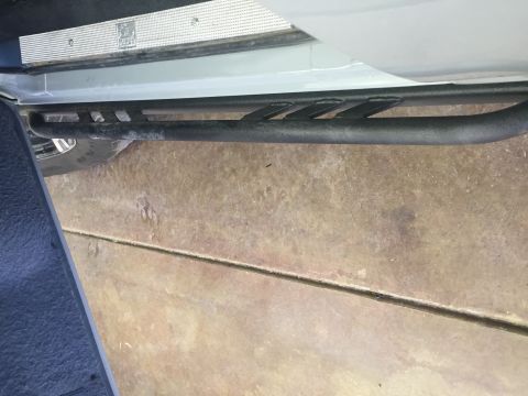 1988 Ford Bronco - A close-up view shows the black tubular side step installed on the lower body of a light-colored vehicle. The side step features a series o…