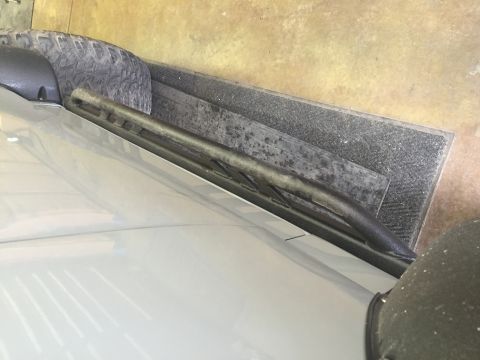 1988 Ford Bronco - A close-up view of a light-colored vehicle's hood and windshield wiper. The vehicle appears to be parked on a textured mat with a tire visi…