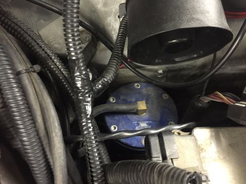 1988 Ford Bronco - A close-up view of the engine bay shows a blue fuel pressure regulator with the Vortech logo, surrounded by various black corrugated hoses…